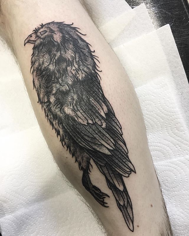 Black tattoo of a crow on the leg