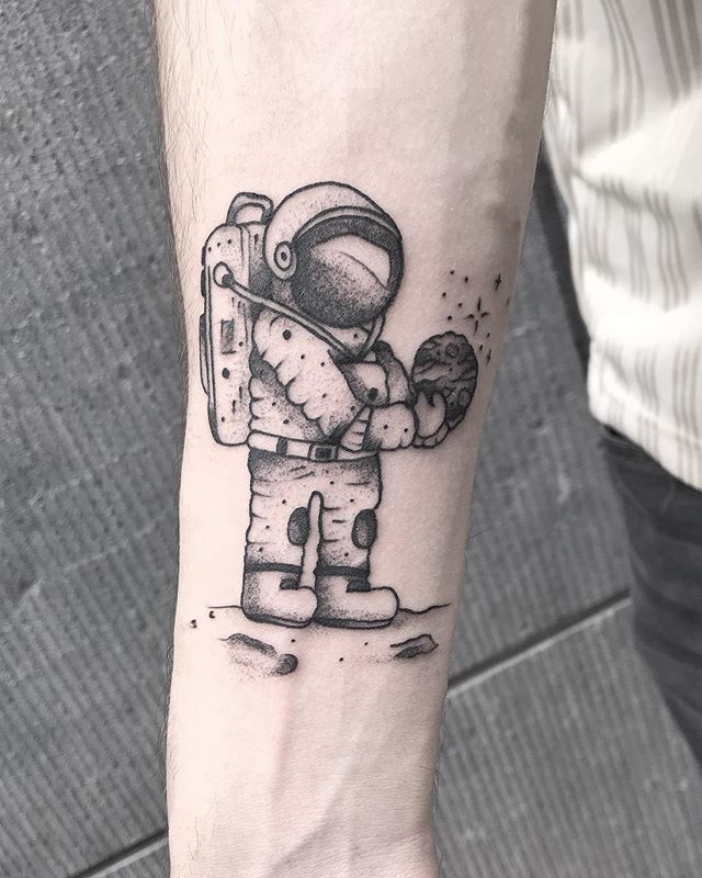 Black tattoo of an astronaut holding a rock on the right hand