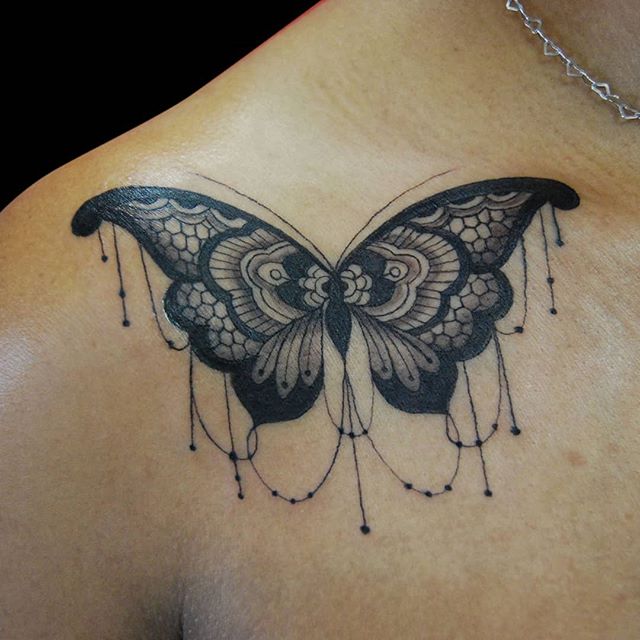 Black tattoo of a butterfly on the right shoulder