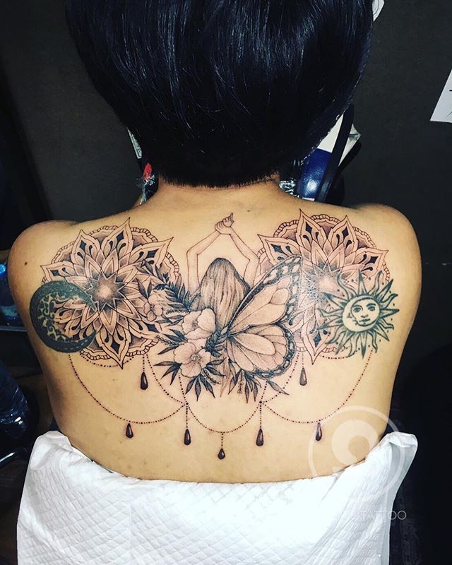 Black and grey tattoo of a girl between flowers, butterfly and sun on the back
