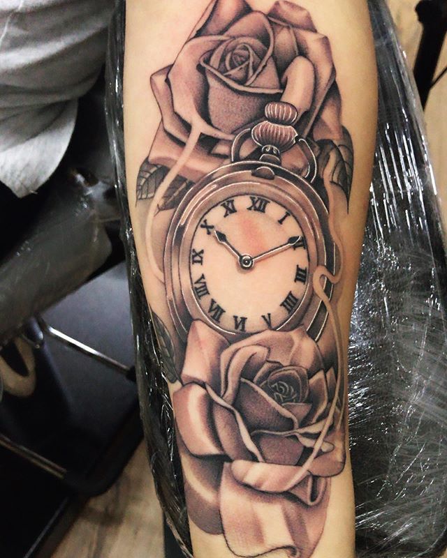 Black and grey tattoo of an old watch with roses on the left hand
