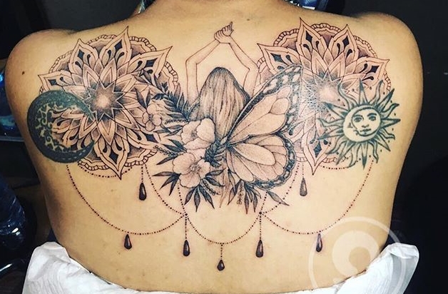 Black and grey tattoo of a girl between flowers, butterfly and sun on the back