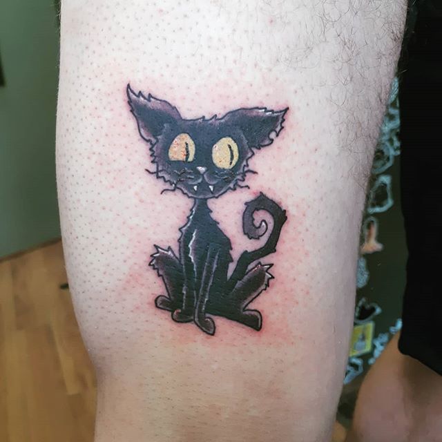 Cartoon tattoo of a black cat on a right leg
