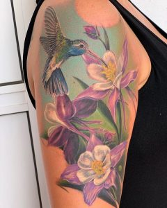 Color tattoo of a hummingbird with flowers on the right hand