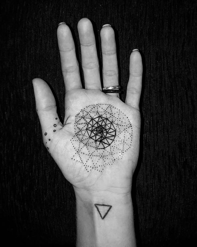 Geometric tattoo of a spiral on the left palm