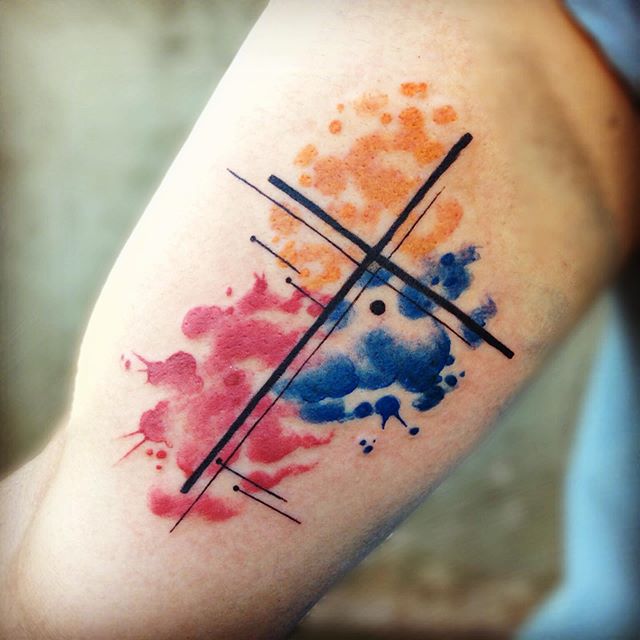 Abstract tattoo of colored blobs with a cross on the right leg