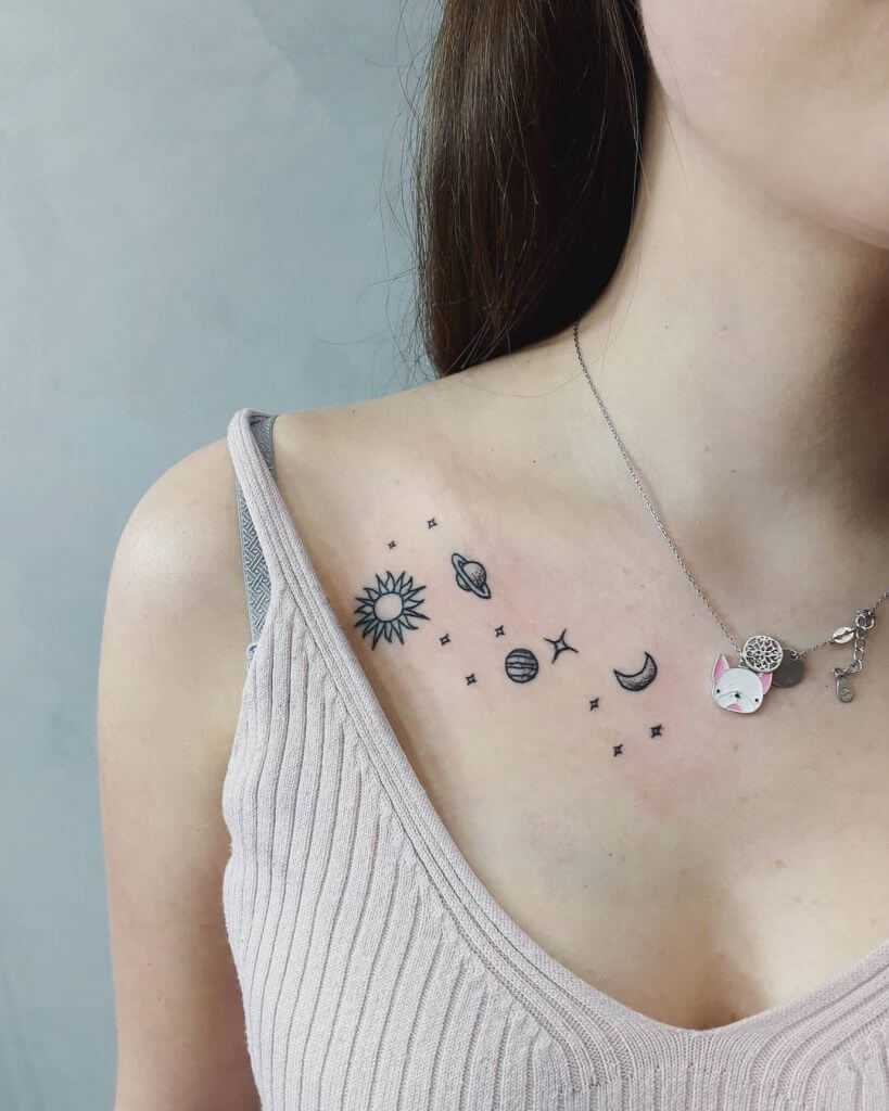 Black tattoo of planets on the collar bone