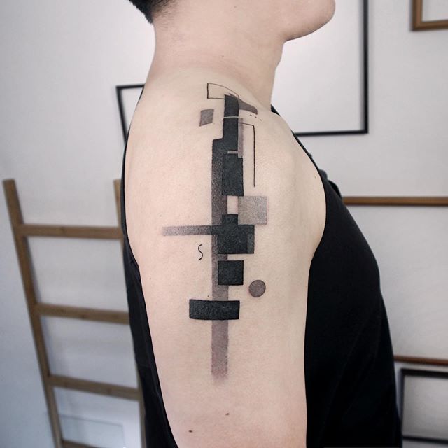 Geometric tattoo of squares, rectangles, and a circle on the right shoulder