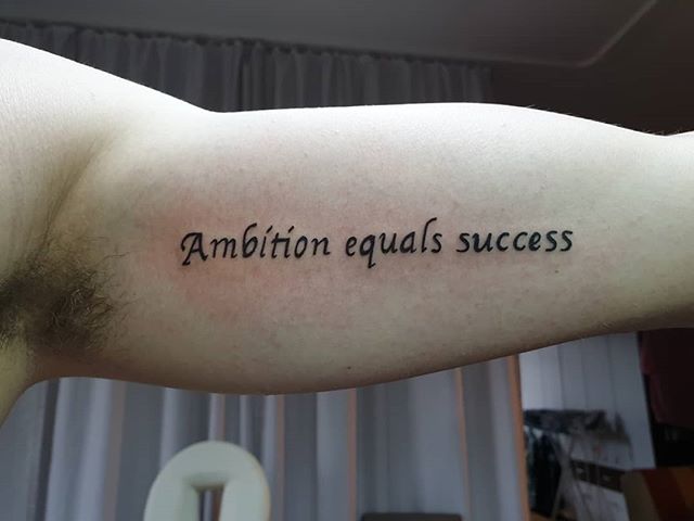Lettering tattoo of "Ambition equals success" on the left hand