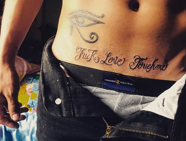 Lettering tattoo of a "fuck love touch me" on the lower abdomen