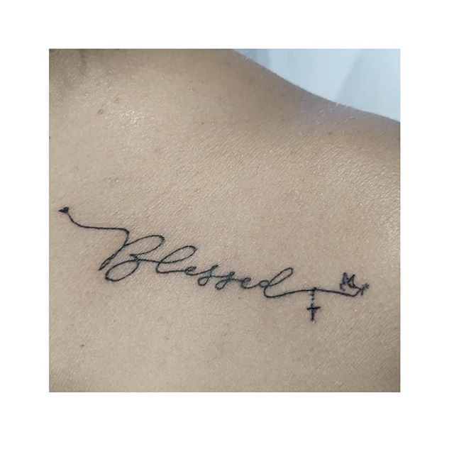 Lettering tattoo of a "blessed" on the left shoulder