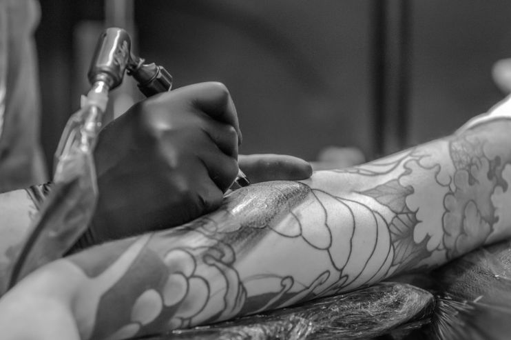 Tattoo artist creating a black and grey tattoo on the hand