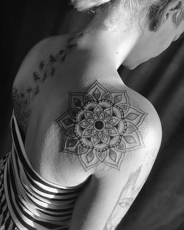Mandala tattoo of a flower on the right shoulder