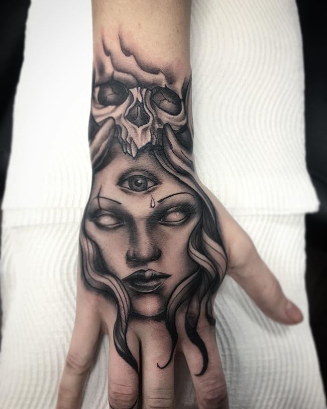Neotraditional tattoo of a female face, with the eye in the middle of the forehead and the skull on the head , on the right hand