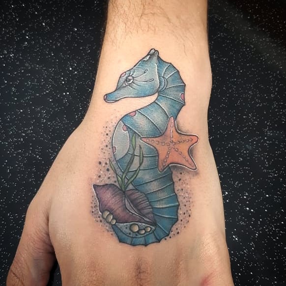 Neotraditional tattoo of a blue sea horse with a starfish and a shell on the left hand