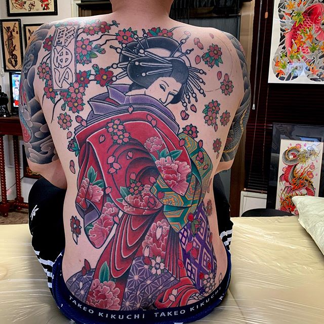 Oriental tattoo of a geisha with lots of flowers on the back