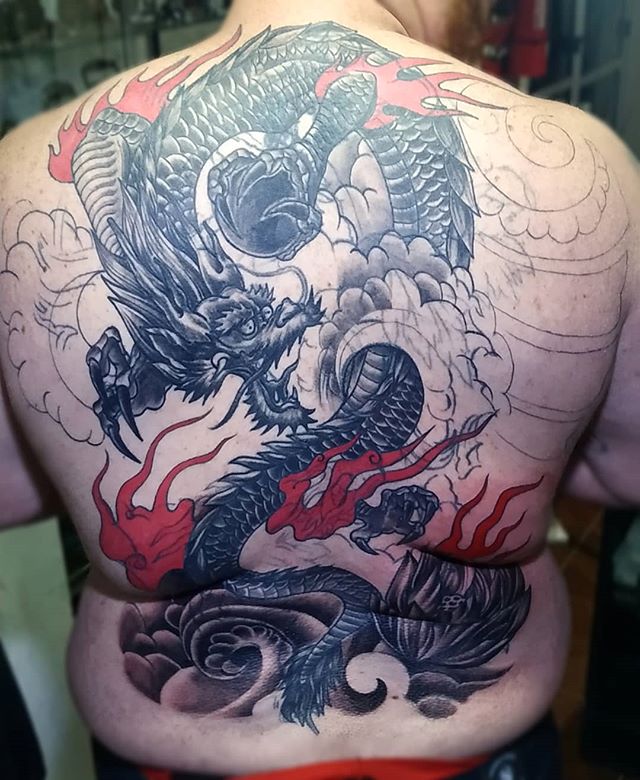 Oriental tattoo of a dragon on fire on the back