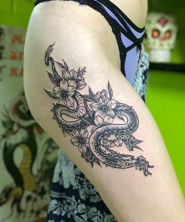 Oriental tattoo of a dragon with Sakura flowers on the right leg