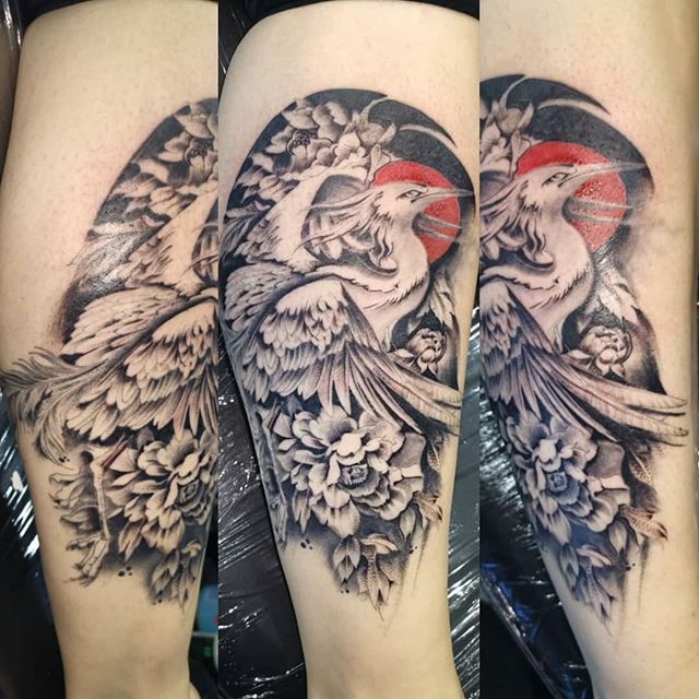 Oriental tattoo of a heron with flowers on the calf
