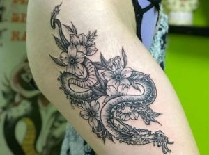 Oriental tattoo of a dragon with Sakura flowers on the right leg