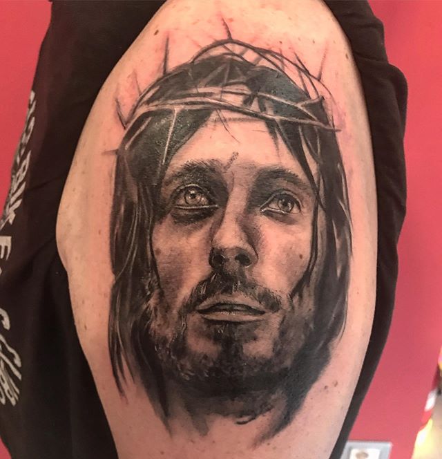 Realistic tattoo of Jesus Christs head on the left arm