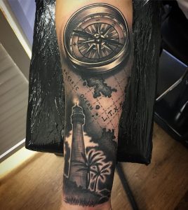 Black Male tattoo of a lighthouse and compass on the right forearm