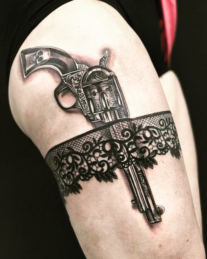3 D tattoo of a gun revolver on the right thigh