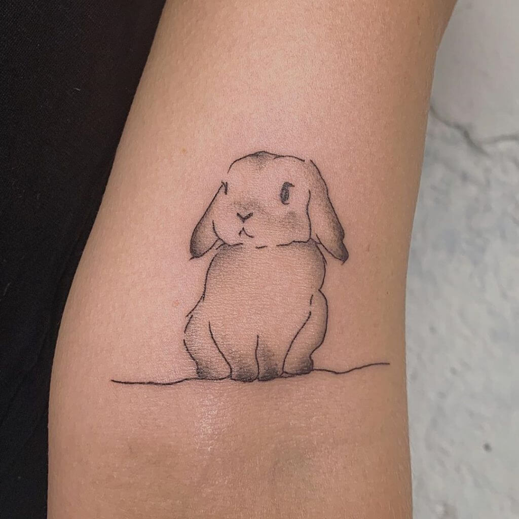 Black Bunny tattoo on the left forearm
