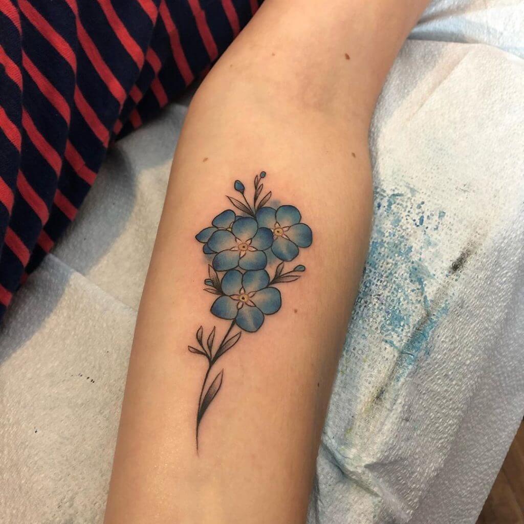 Forearm tattoo of blue flowers