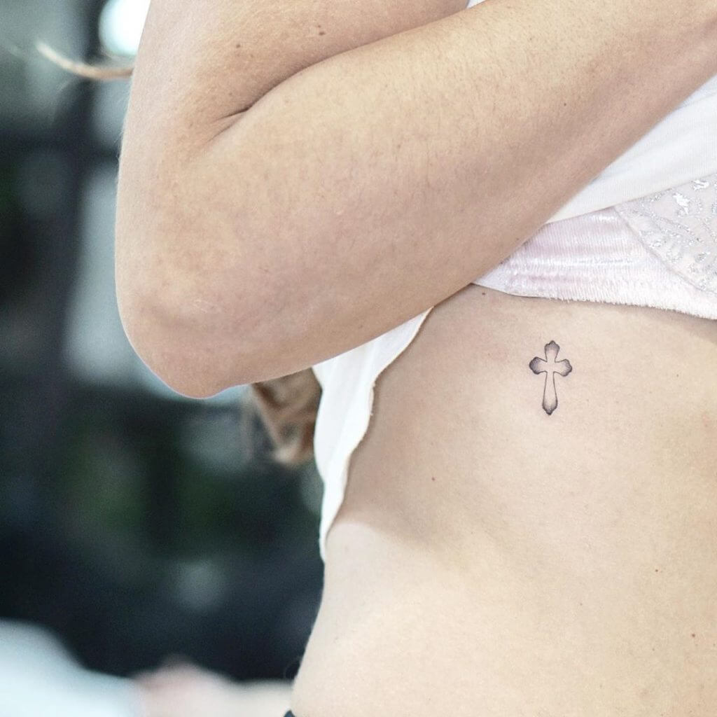 Small Black tattoo of a cross on the ribs