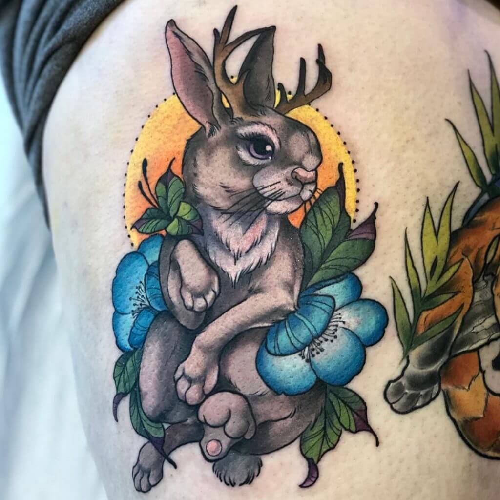 Color tattoo of a bunny with antlers and a flowers on the ribs