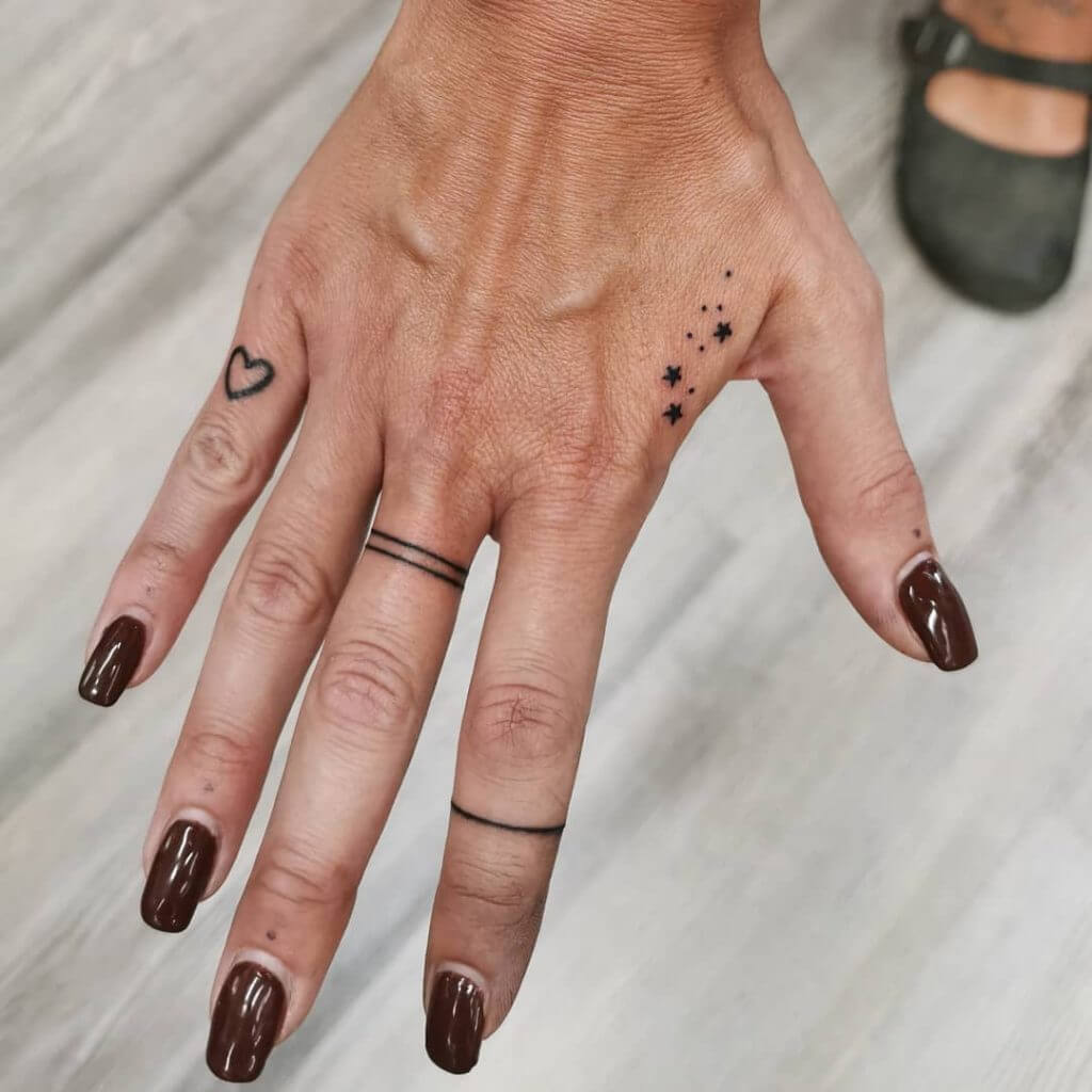 Small Black tattoos of stars, a heart and lines on the right hand