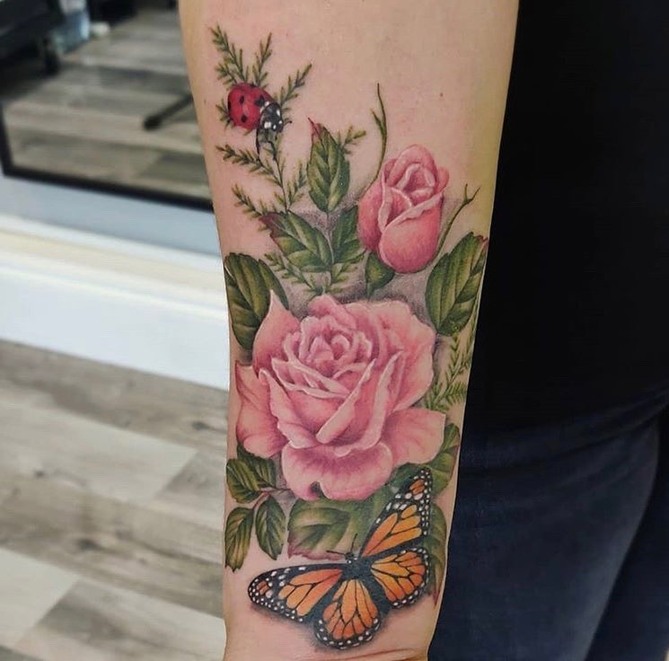 Color forearm tattoo of pink roses, a butterfly and a ladybug