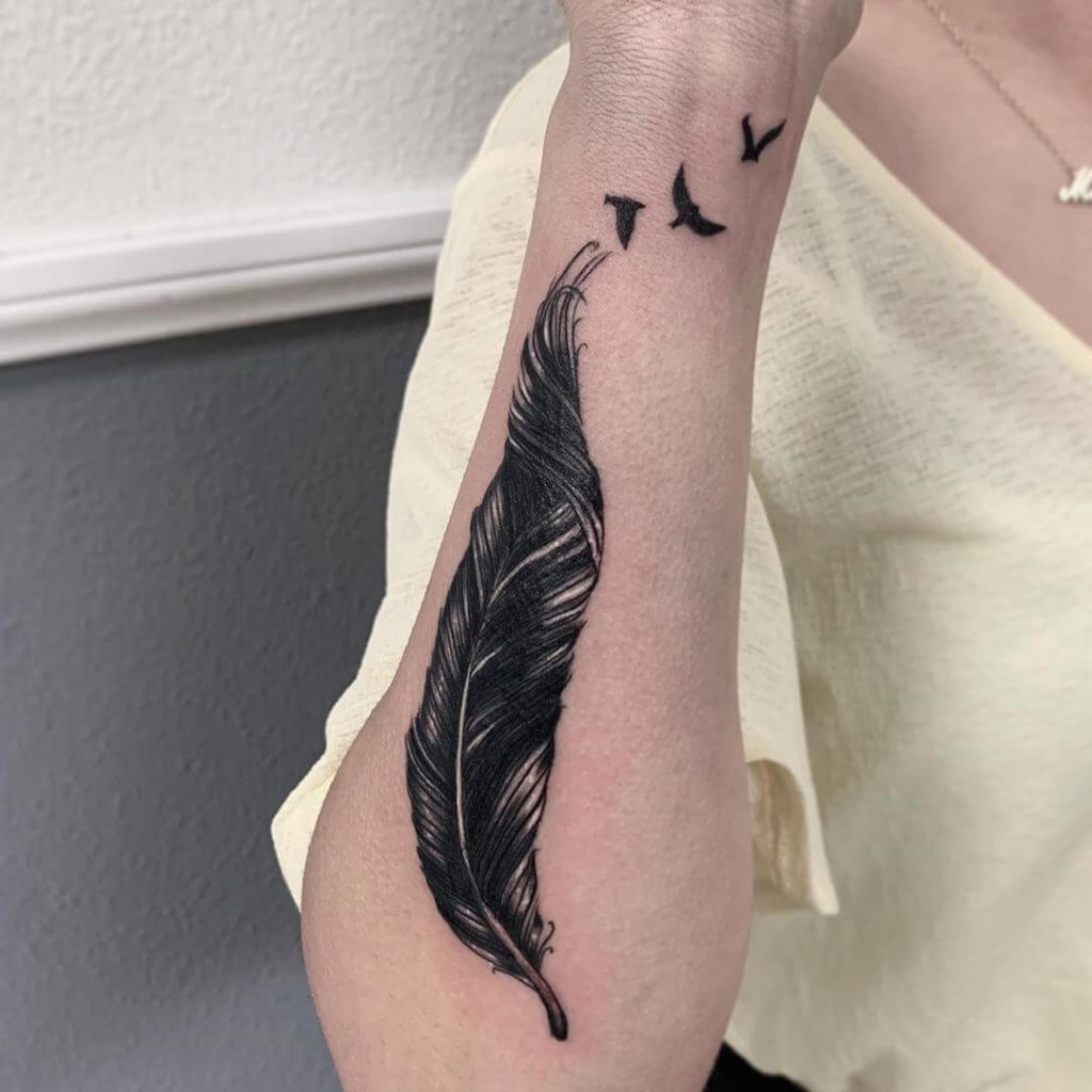 Black Forearm tattoo of a feather and birds