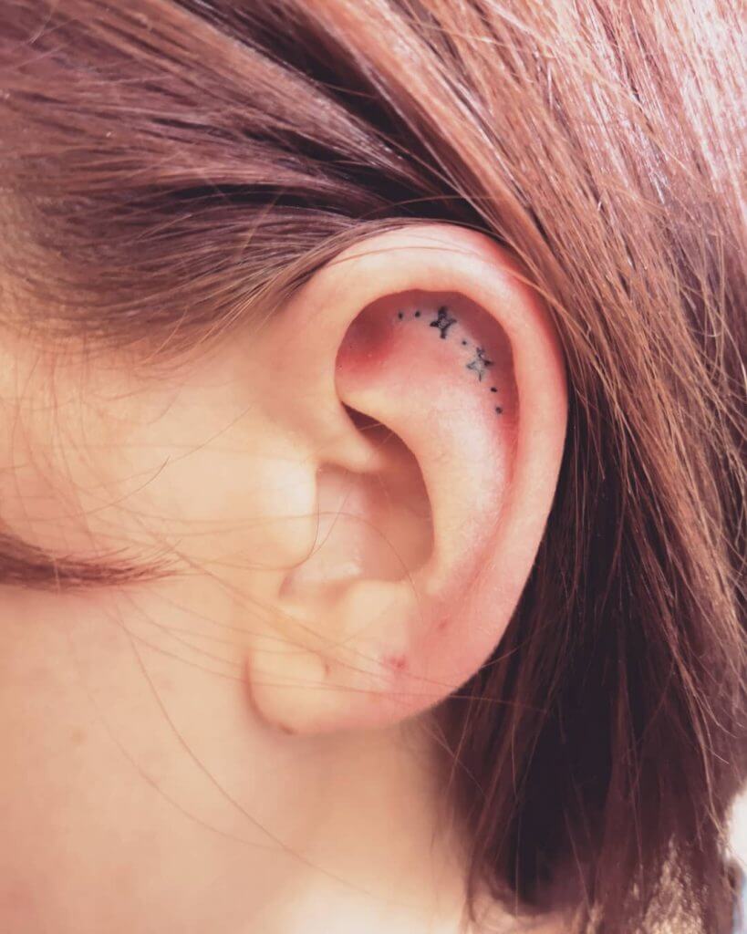 Small Black tattoo of stars on the ear