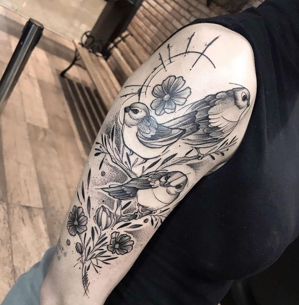 Black tattoo of birds and flowers on the right arm