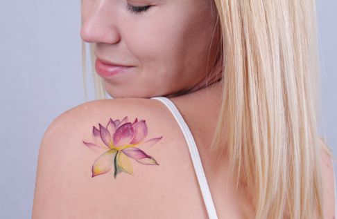 Blonde woman with color flower tattoo on the shoulder