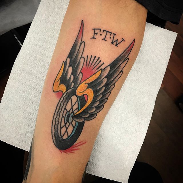 Traditional color tattoo of a wheel with wings on the leg