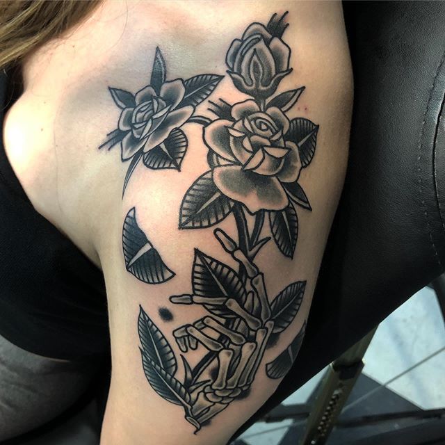 Traditional tattoo of roses on a hand of a skeleton on the left shoulder