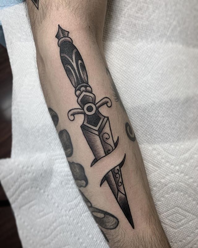 Traditional tattoo of a dagger on a forearm