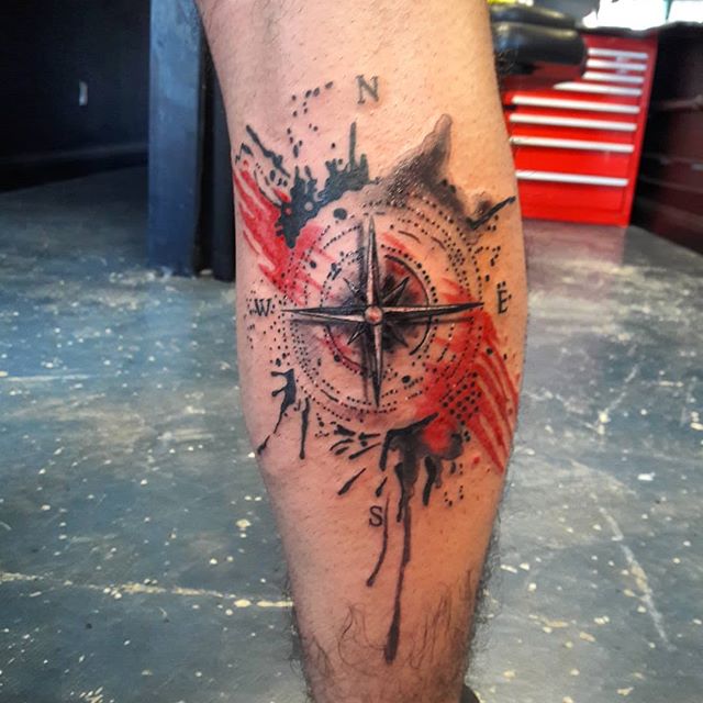 Trash polka tattoo of a compass on the left leg
