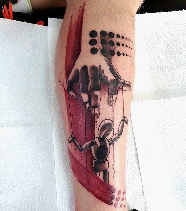 Trash polka tattoo of a marionette puppet suspended from a hand, on the right calf