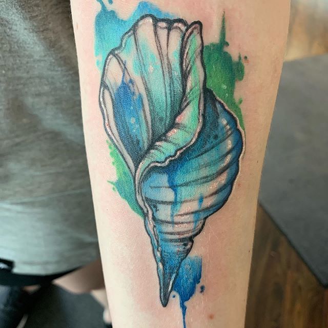 Watercolor tattoo of a seashell on the left forearm