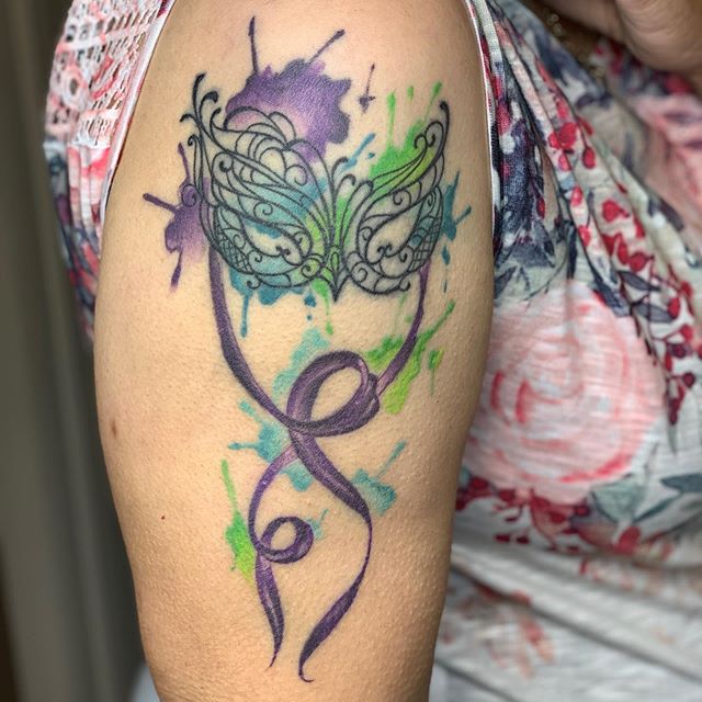 Watercolor tattoo of a female mask on the right arm