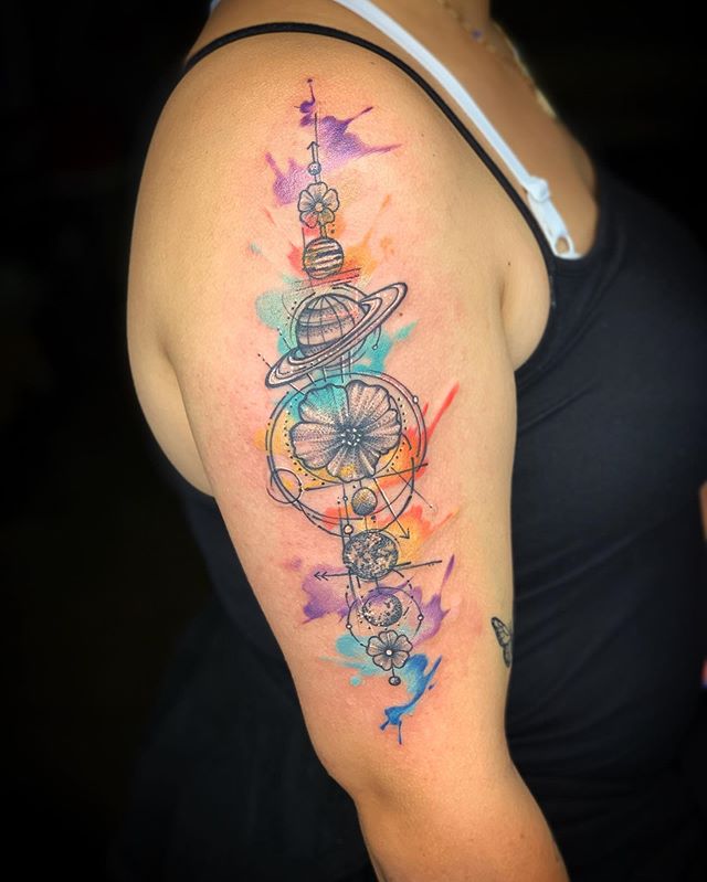 Watercolor tattoo of flowers and planets on the right arm
