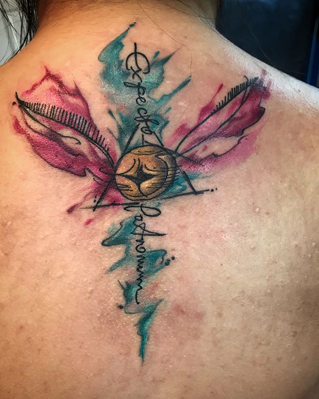 Watercolor tattoo of a Golden Snitch on the back