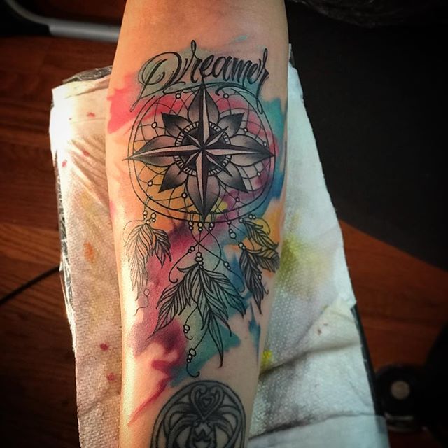 Watercolor tattoo of a dream catcher with a compass star on the forearm