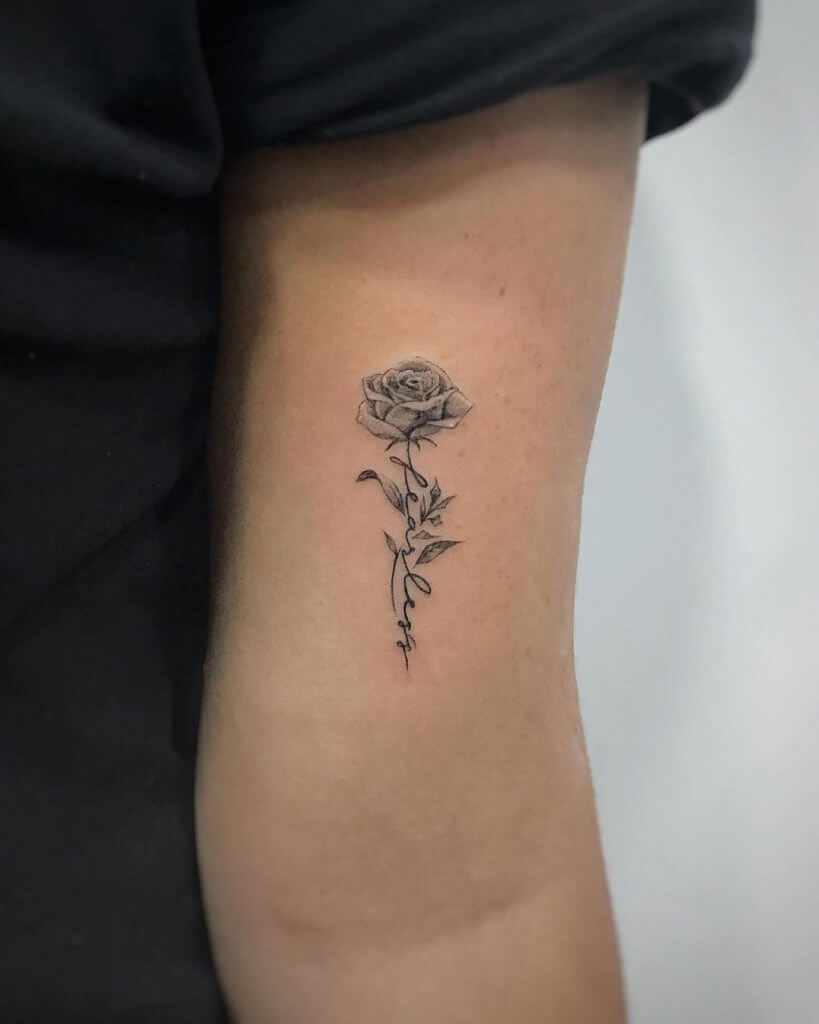 A small black rose tattoo of a rose on the hand