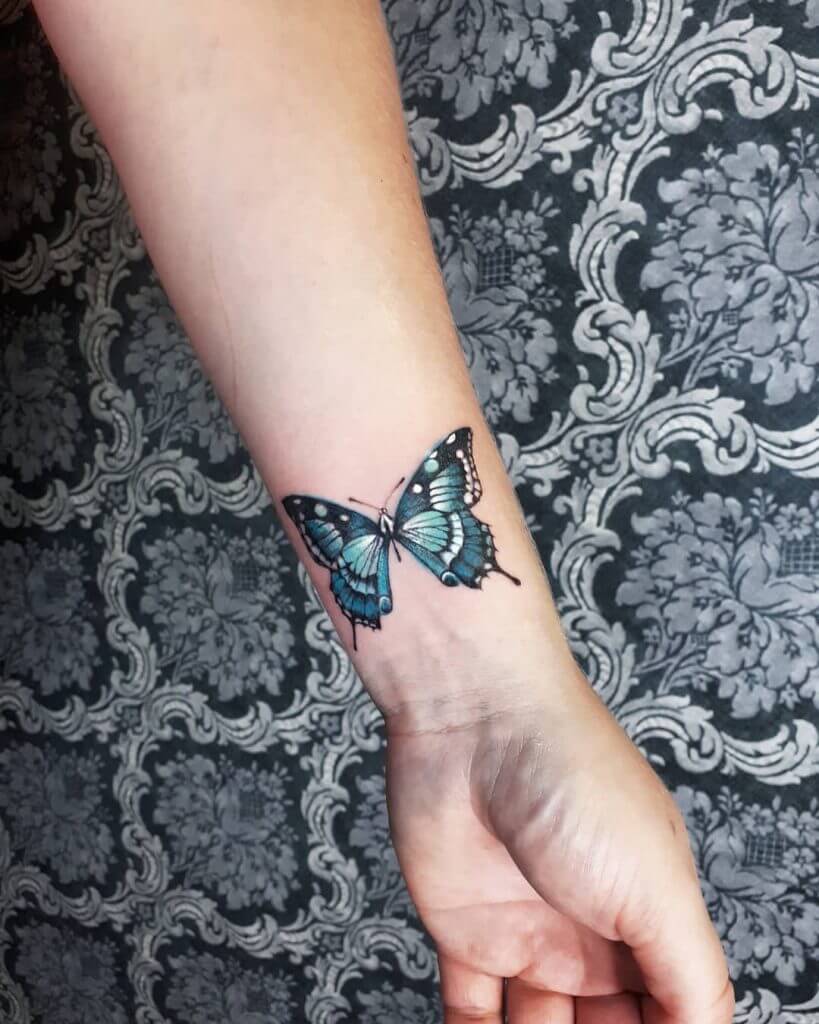 Color Butterfly tattoo on the left forearm