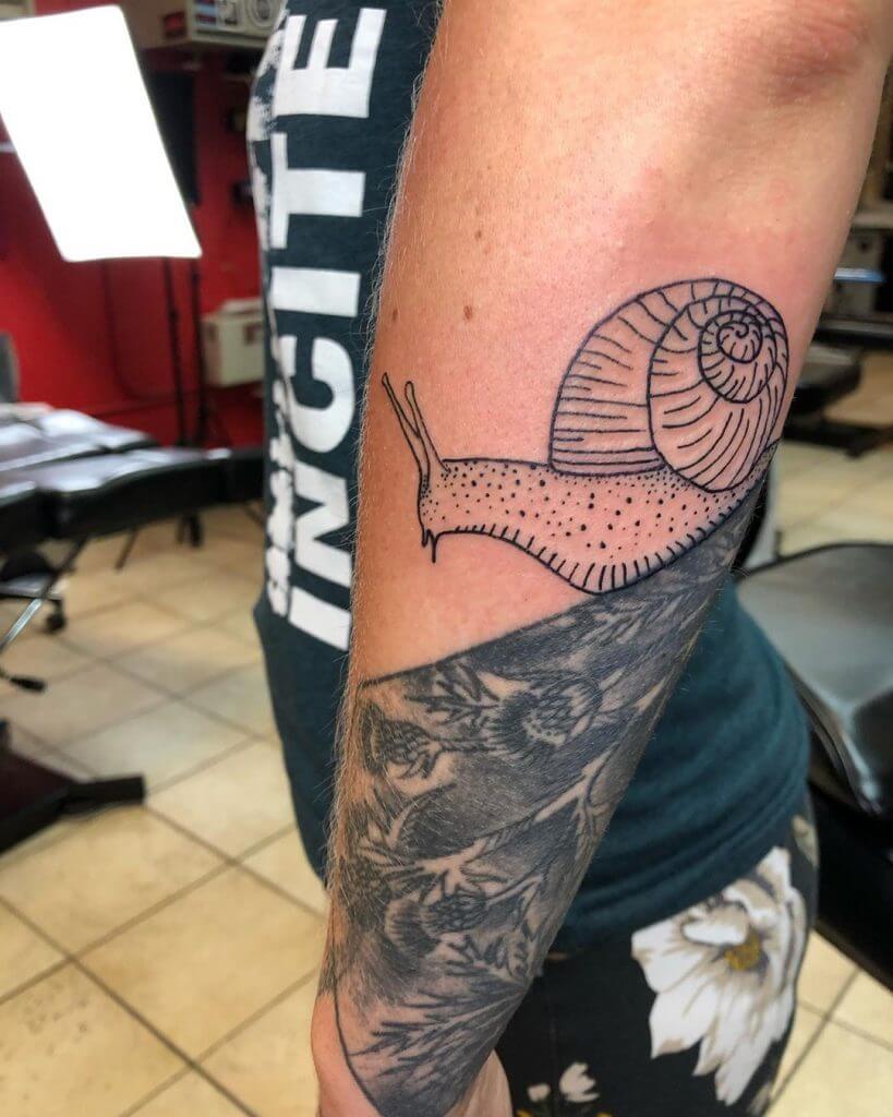 Black Animal tattoo of a snail on the left forearm